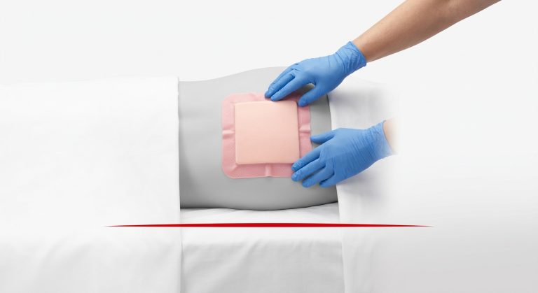 Cinematic photo of a nurse offloading a patient’s heels while protective silicone foam dressings are applied to pressure-prone areas.